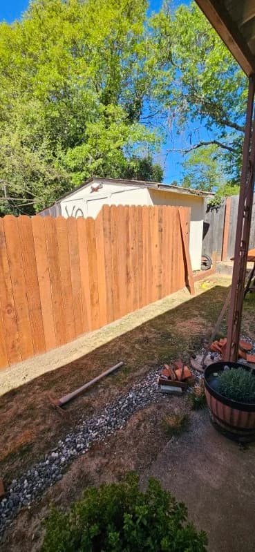 Completed natural-cedar privacy fence viewed from a covered patio with a potted lavender — Maples Landscaping, Mendocino County